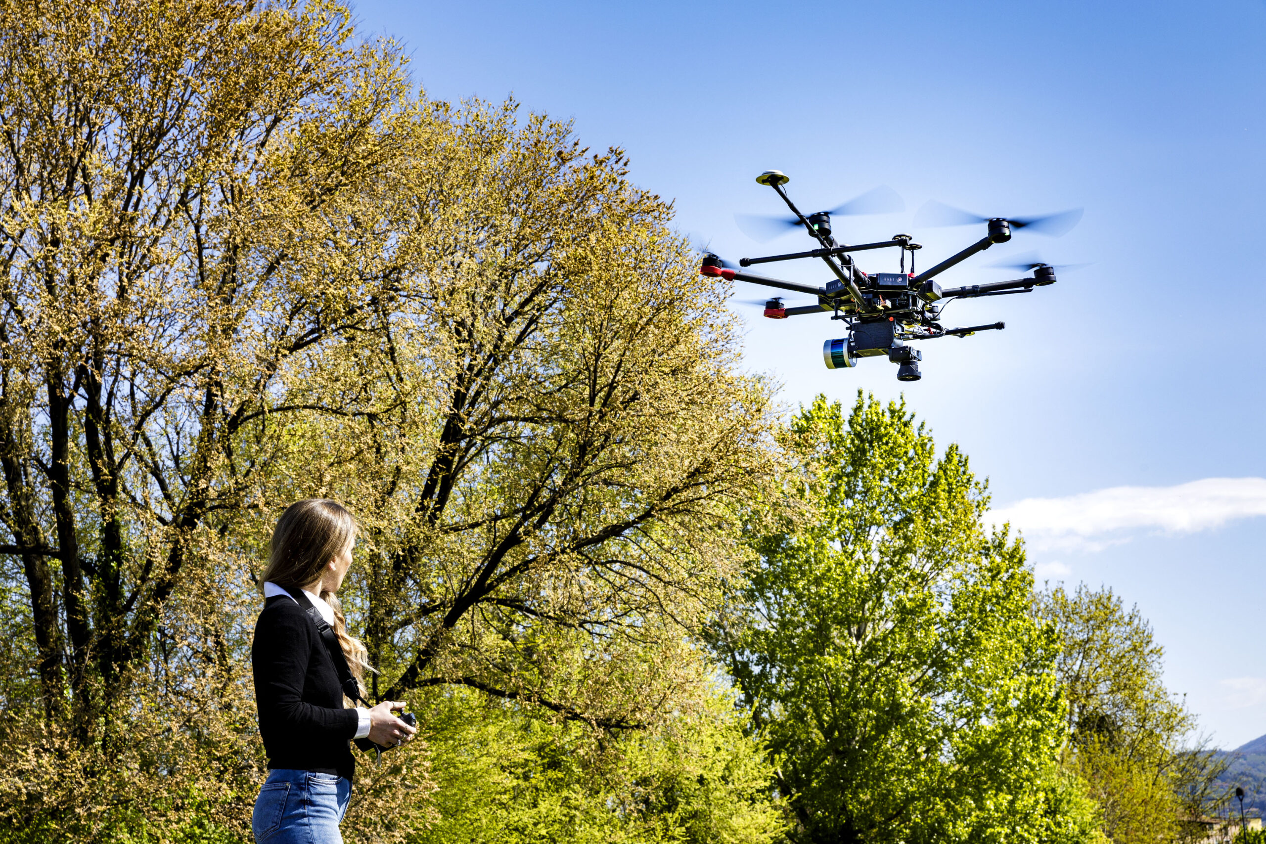 A drone flying while a person controls it from the ground